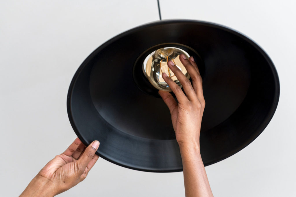 Close up of hand replacing light bulb in a pendant lamp
